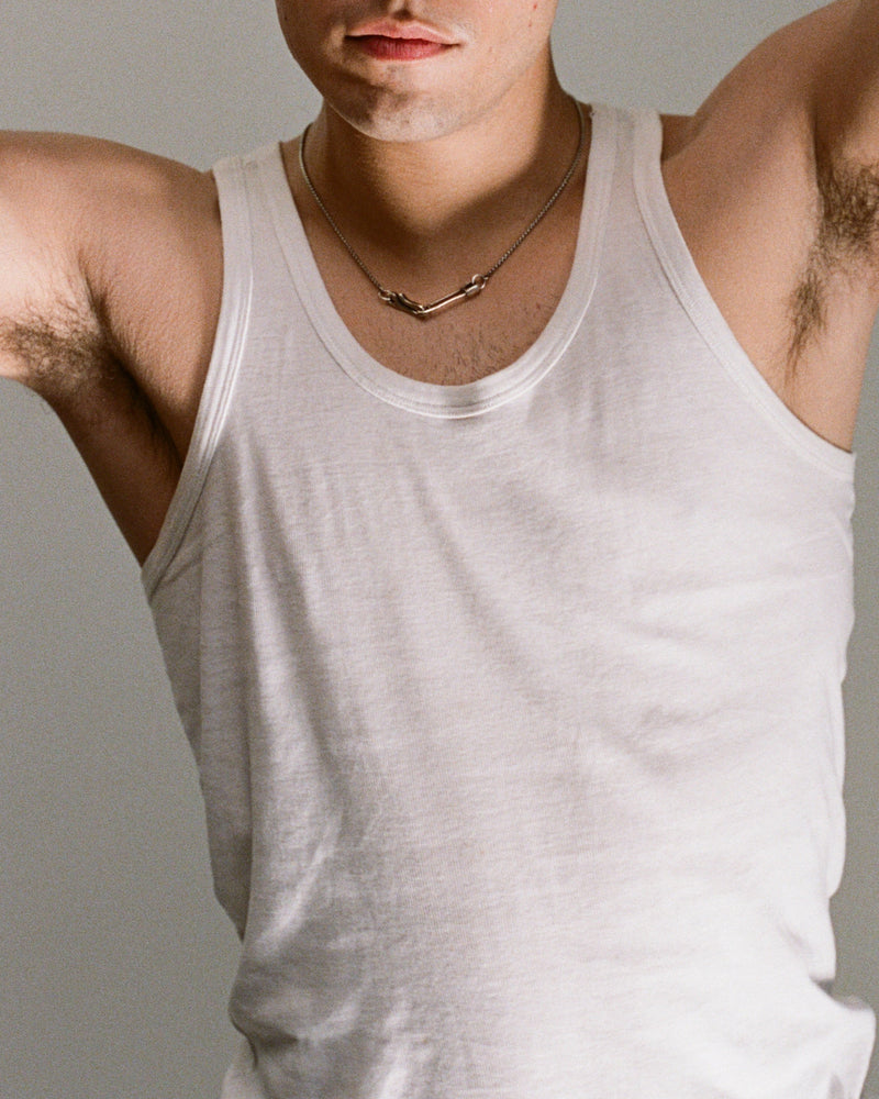 Man wearing a white tank top with a neutral background