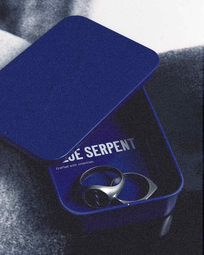 Blue Serpent jewelry box with a ring inside on a textured surface