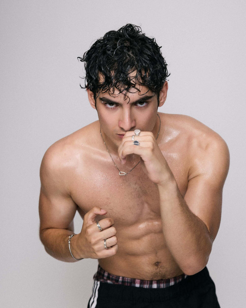 Muscular man posing with a confident expression on a plain background with 925 silver jewelry (necklace and rings and bracelet)
