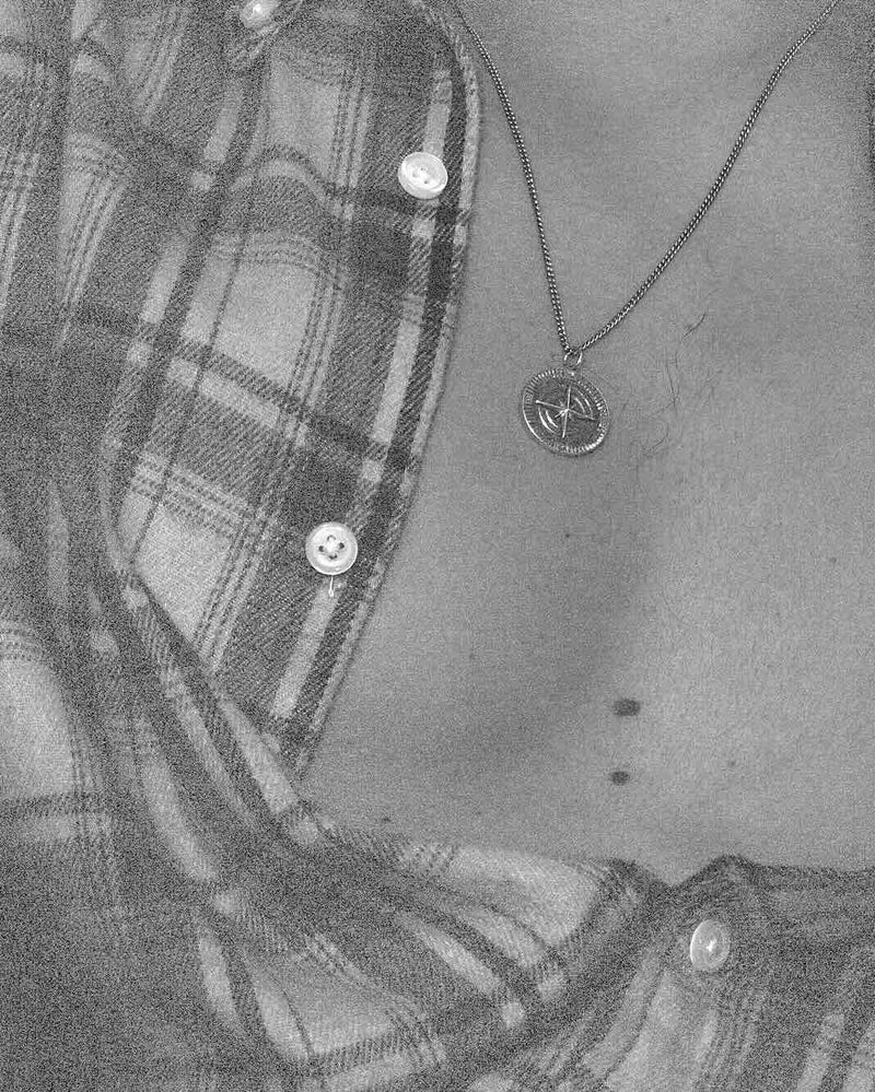 Person wearing a plaid shirt with a necklace and visible male's jewelry.