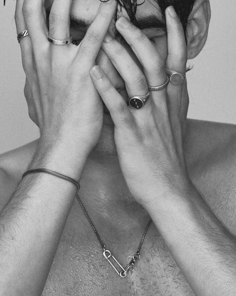 Black and white photo of a person with hands covering their face against a plain background