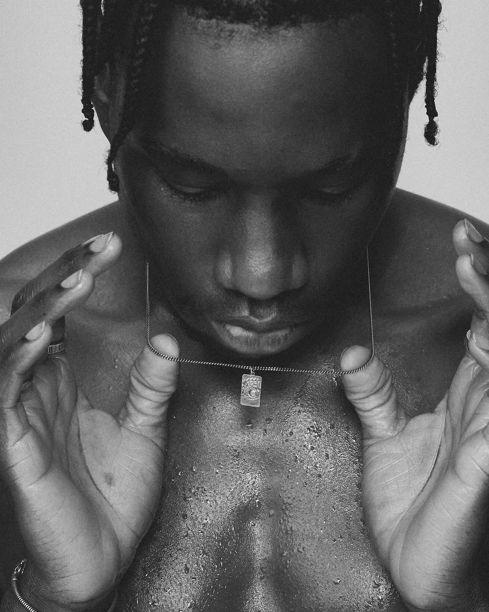 Black and white portrait of a person with braided hair holding a necklace that is 925 silver,
