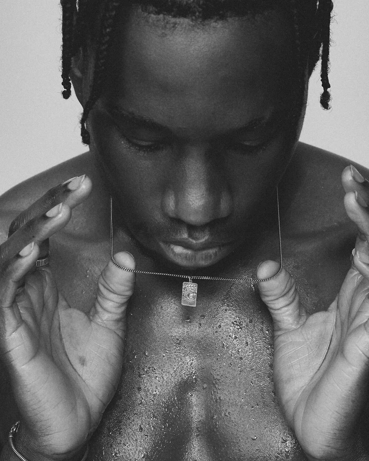 Black and white portrait of a person with braided hair holding a necklace that is 925 silver,