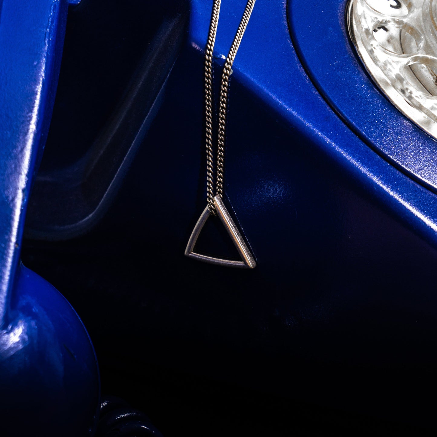 blue serpent triangle necklace on blue phone