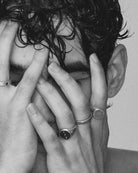 Black and white photo of a person with hands covering their face against a plain background wearing 925 silver jewelry