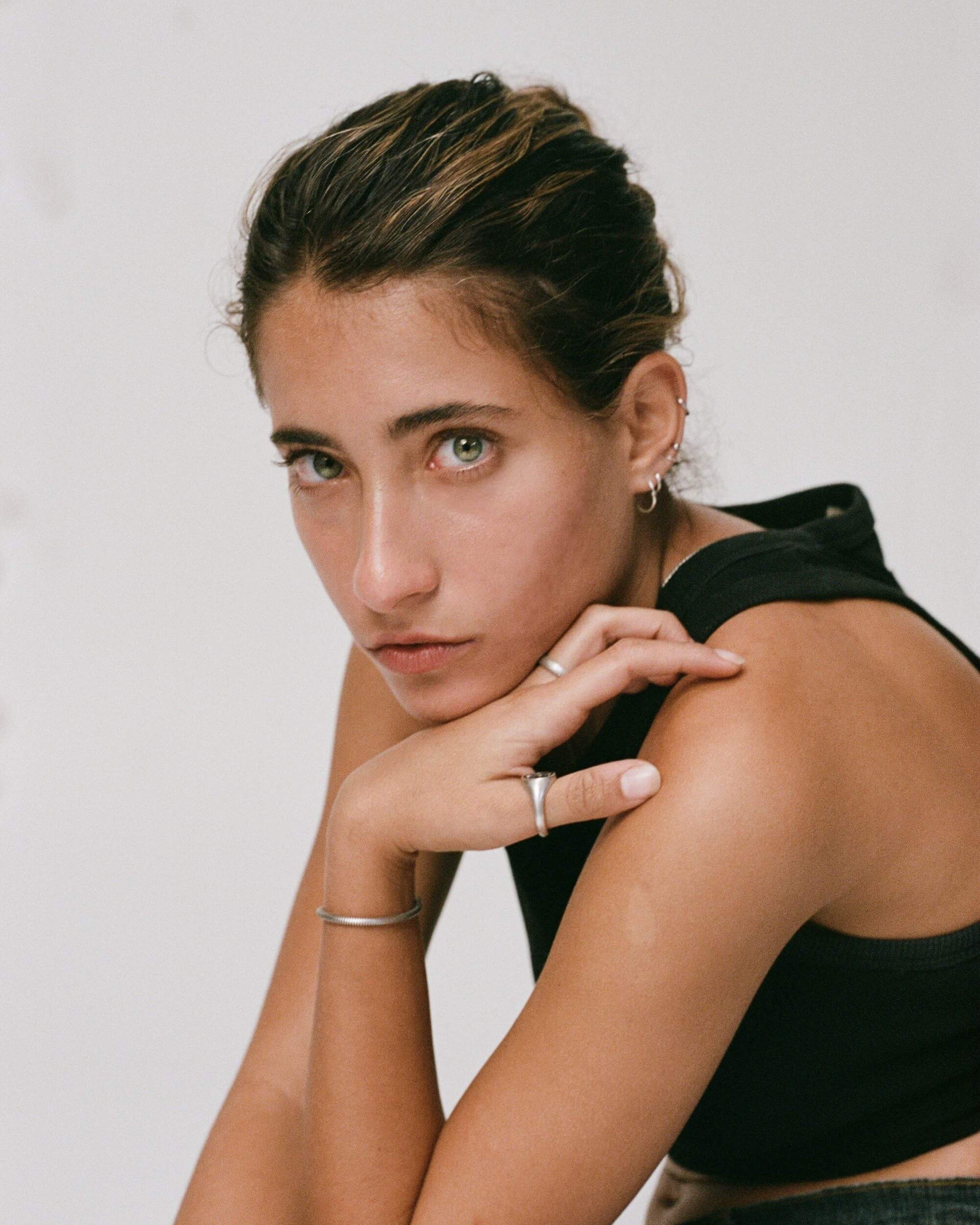 Woman wearing a black sleeveless top against a plain background wearing 925 silver blue serpent rings